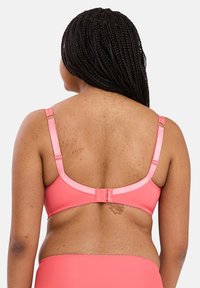 Roze bh met verstelbare bandjes, gladde stof en een haak-en-oogsluiting. Het ontwerp heeft een naadloze achterkant en een zachte textuur.