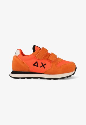 Fel oranje kindersneaker met twee klittenbanden, zwarte geometrische symbolen aan de zijkant, een wit hielstuk en een zwart profiel onder de zool.