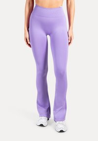 Lila Leggings mit hohem Bund aus einem glatten, dehnbaren Stoff mit ausgestelltem Beinabschluss. Gepaart mit weißen Sportschuhen, ohne sichtbare Muster.