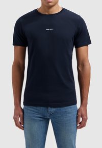 Marineblauwe katoenen T-shirt met korte mouwen, een ronde hals en witte "PURE PATH" tekst op de voorkant gedrukt.