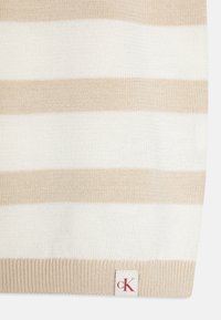 Maglione a righe beige e bianche con orlo a coste, realizzato in morbido materiale di maglia. Presenta un piccolo etichetta con "cK" in rosso.