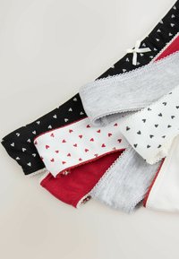 Cinque chiloți de bumbac pentru femei, în negru, alb, roșu și gri, cu modele mici de inimioare și margini dantelate, aranjați suprapuși pe un fundal deschis.