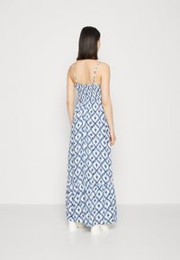 Sukienka maxi w niebiesko-białym wzorze w romby, z cienkimi ramiączkami, dopasowanym korpusem i warstwowym, falbanym dołem. Lekki materiał o gładkiej teksturze.