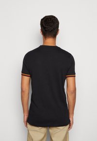 Black short-sleeve t-shirt featuring a round neck, with red, yellow, and black striped accents on the sleeves. Cotton material, casual fit.