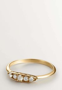 Anillo de oro con banda lisa, que presenta tres piedras lunares redondas y dos diamantes engastados en un bisel ovalado pulido.