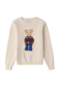 Crème-kleurige trui met een teddybeer motief gekleed in een bruine jas en blauwe broek, met gebreide textuur en geribde manchetten.