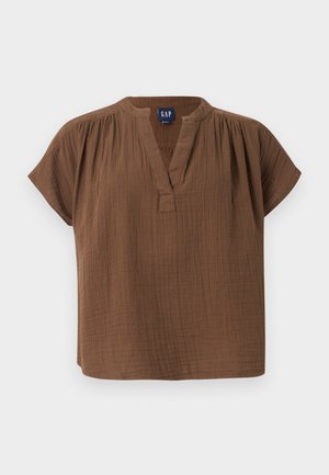 Καφέ βαμβακερό μπλουζάκι με κοντά μανίκια, V-λαιμόκοψη και λεπτομέρειες με πτυχώσεις στους ώμους, με ετικέτα GAP, απεικονίζεται σε απλό ανοιχτό φόντο.