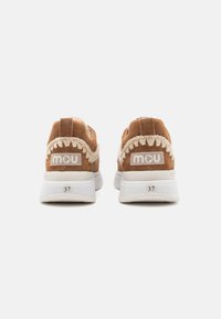 Baskets en suede marron avec semelles en caoutchouc blanches, avec un accent tissé autour du talon et un détail de logo à l'arrière. Taille 37.