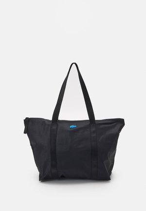 Sac cabas noir en matériau durable, doté de deux anses noires, d'une fermeture éclair et d'un petit logo bleu sur le devant.