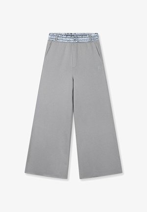 Pantalones de pierna ancha de color gris claro con cintura elástica que presenta un detalle texturizado azul. Incluye bolsillos laterales y un sutil detalle de logotipo.