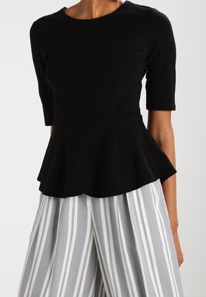 Czarny top z baskinką i krótkimi rękawami, wykonany z gładkiej tkaniny. Połączony z szerokimi spodniami w szare i białe paski. Prosty, okrągły dekolt.