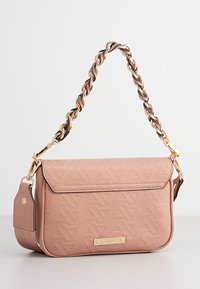 Růžová crossbody taška vyrobená z texturovaného syntetického materiálu. Obsahuje řetízkový popruh a zlatý kovový akcent na přední straně.