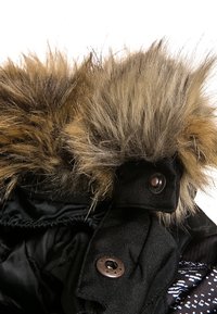 Czarna pikowana kurtka puchowa z odpinanym kapturem wyłożonym futerkiem. Kurtka posiada brązowe futro, srebrne guziki oraz teksturowaną tkaninę. Akcenty w kolorach czarnym i białym.