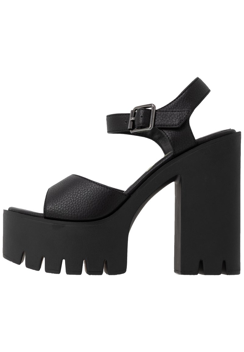 Sandale à plateforme noire à talons hauts épais avec des brides texturées et une fermeture à boucle ajustable autour de la cheville.