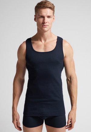 Navyblaues, geripptes Tanktop mit breiten Schulterträgern, das eine taillierte Passform und eine glatte Textur aufweist, kombiniert mit passenden dunklen Shorts.