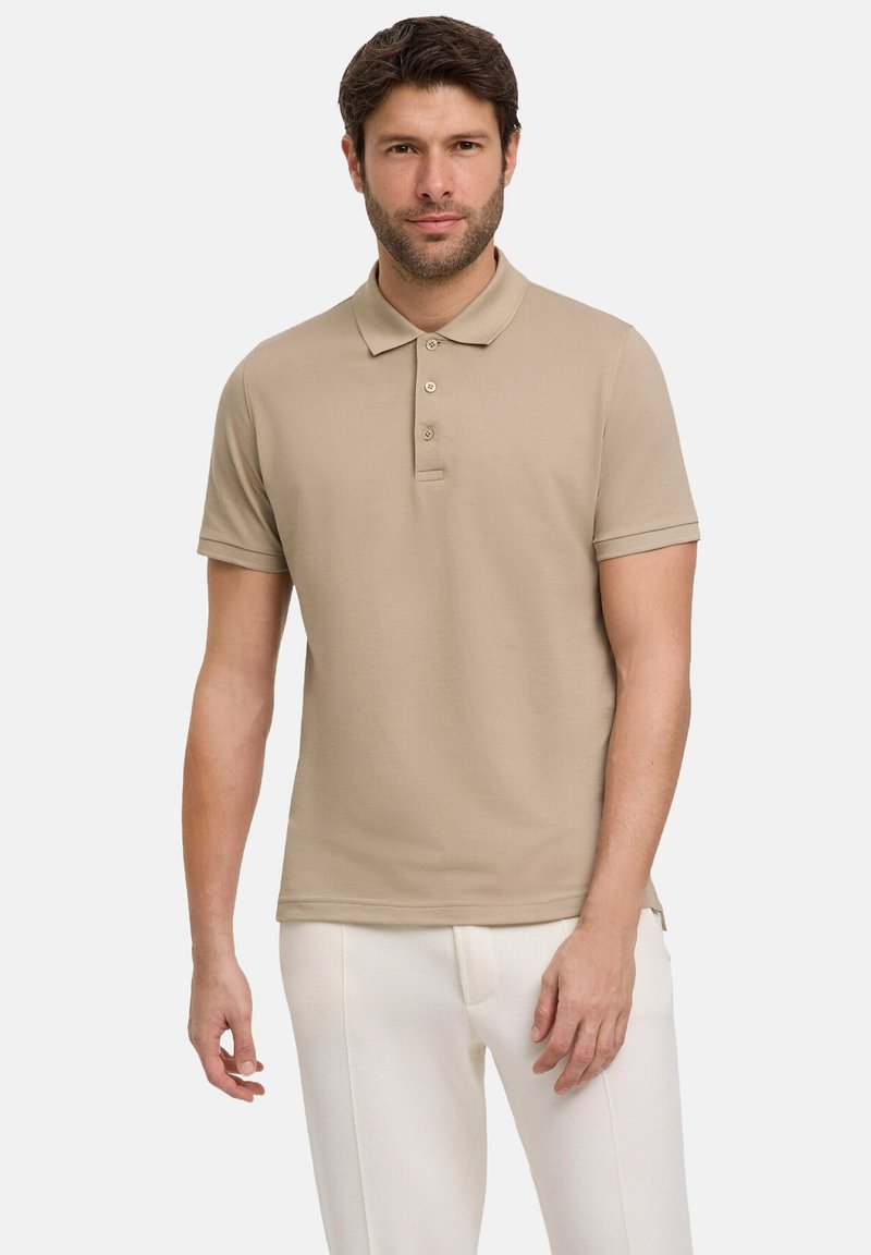 Beige polo shirt met een kraag, drie-knopenpasvorm, korte mouwen en een gestructureerde stof, gecombineerd met witte broek voor contrast.