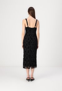 Μαύρο φλοράλ μίντι φόρεμα με διάφανη υφή, ρυθμιζόμενες τιράντες και άνοιγμα στο πίσω μέρος. Οι λεπτομέρειες περιλαμβάνουν διακριτά σχέδια τριαντάφυλλου και λεπτές τιράντες.