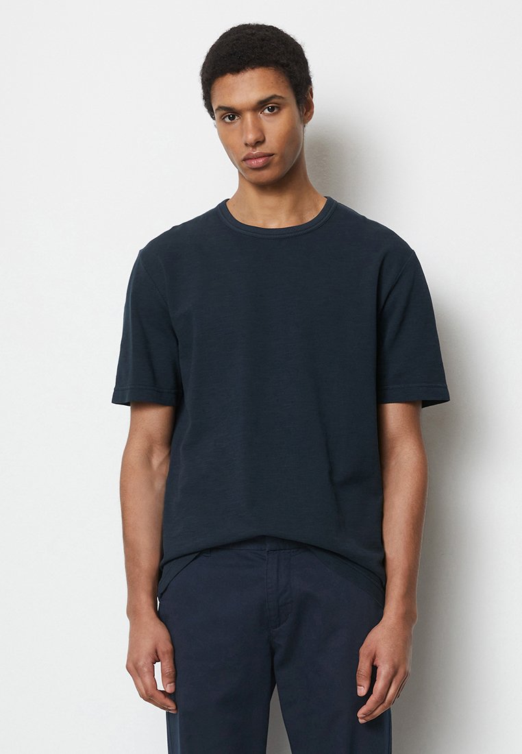 Granatowa bawełniana koszulka z krótkim rękawem, okrągłym dekoltem i luźnym krojem. Gładka tekstura, minimalistyczny design i brak widocznych wzorów.