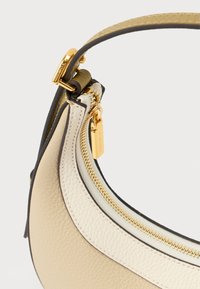 Mala de couro bege e creme com fecho e ferragens douradas, apresentando uma superfície texturizada e uma fixação de alça curvada.