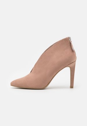 Chaussure à talons hauts en daim rose pâle avec un bout pointu et une fermeture éclair à l'arrière. Design élégant avec une texture lisse.
