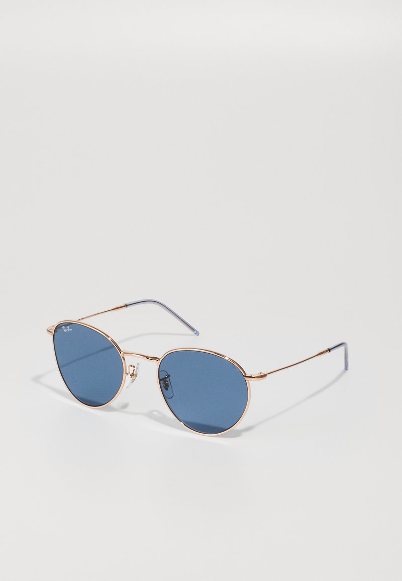 Ochelari de soare cu ramă metalică aurie și lentile cu nuanță albastră. Design oval, cu brațe subțiri și accente din cauciuc la vârfuri pentru confort.