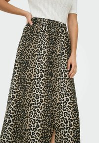 Midi sukně s leopardím vzorem a elastickým pasem, s černými knoflíky vpředu a bočním rozparkem pro větší detaily.
