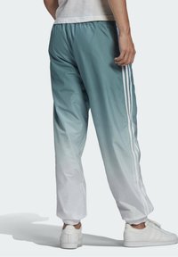 Lättvikts-ombre träningsbyxor i teal till vitt, med elastisk midja, muddade fotleder och tre vita ränder längs sidorna.