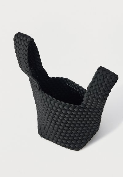 Μαύρο υφαντό καλάθι αποθήκευσης με ανυψωμένες λαβές, κατασκευασμένο από υλικό με υφή. Το σχέδιο έχει κυλινδρικό σχήμα και ανοιχτό πάνω μέρος.