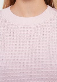 Pull rose clair en maille avec une texture côtelée. Présente un col large et arrondi ainsi qu'un motif horizontal régulier.