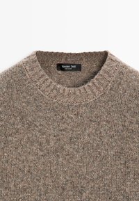 Pull marron tricoté col rond avec col côtelé et étiquette Massimo Dutti cousue à l’intérieur de l’encolure.