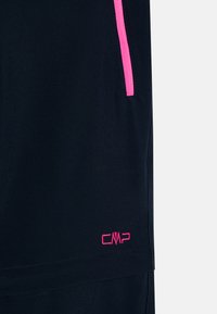 Tamno plavi šorti s kontrastnim ružičastim patentnim zatvaračem. Ima CMP logo u ružičastoj vezici blizu rubа. Mekana, glatka tekstura tkanine.