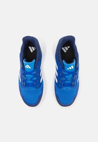 Modré sportovní boty s texturovaným síťovým svrškem, námořnickými akcenty a bílými pruhy. Mají polstrovanou podrážku a kontrastní černou stélku.