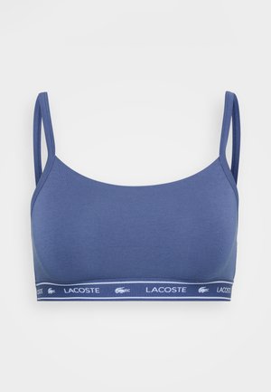 Niebieski bawełniany biustonosz z cienkimi ramiączkami i elastycznym paskiem z logo z białą paskiem. Gładka tekstura i dopasowany krój.