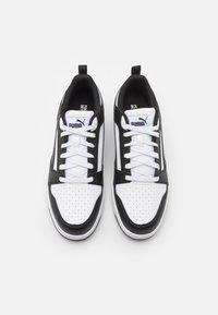 Pár černobílých nízkých sneakers Puma s bílými tkaničkami, perforovanou špičkou a logem na jazyku, viděno z vrchu.
