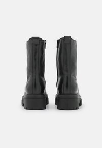 Stivali ankle neri in pelle con finitura liscia, dotati di chiusura con zip sul lato e suola in gomma spessa per maggiore stabilità.