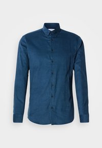 Chemise homme à manches longues bleu foncé, boutonnée, avec col boutonné et boutons noirs sur fond uni.