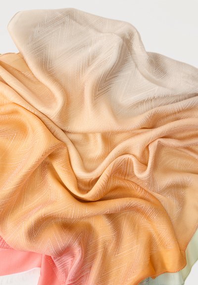 Μαλακό ύφασμα σε αποχρώσεις ροδάκινου, κρέμας και κοραλλιού, με διακριτικά ζιγκ-ζαγκ σχέδια και απαλά ζάρια σε ανοιχτό φόντο.