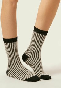Chaussettes rayées en noir et gris, avec une texture côtelée, des revers et des bouts de pied noirs contrastants, et une longueur jusqu'au mi-mollet.