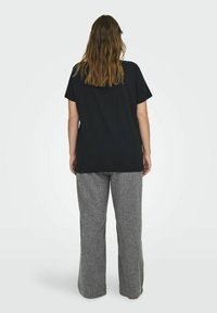 Juodos medvilnės marškinėliai su trumpomis rankovėmis, derinami su pilko langelio rašto plačiomis kelnėmis. Audinys atrodo minkštas ir šiek tiek tekstūruotas.