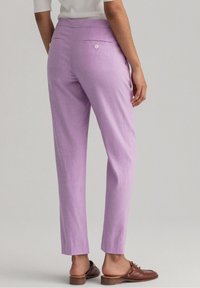 Levandulové kalhoty s úzkým střihem, přední kapsy a dvě zadní kapsy s knoflíkovým zapínáním. Hladká tkanina s módním zpracováním.