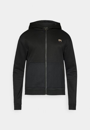 Black zip-up hoodie with a front pocket, mesh texture on the lower panel, and a small logo on the upper left chest. Smooth fabric.