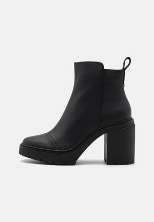 Black leather ankle boot with a rounded toe, chunky block heel, and textured sole. Features a pull tab at the back for easy wear.