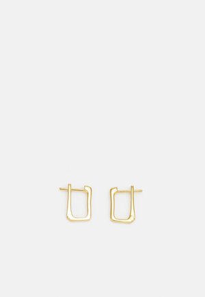 Boucles d'oreilles en métal doré en forme de carré irrégulier, avec une finition lisse et une tige fine pour le maintien.