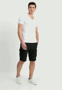 T-shirt branca de decote em V, calções cargo pretos com bolsos laterais e sapatilhas brancas. Design simples com um corte descontraído.