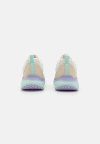 Zapatillas deportivas con una parte superior de malla de color beige claro y blanco, acentos en turquesa y una suela de degradado púrpura. La vista trasera muestra la marca y una asa de agarre.