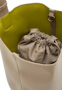 Borsa in pelle beige con un esterno testurizzato e un interno verde brillante in contrasto. Include un sacchetto di stoffa beige con cordoncino all'interno.