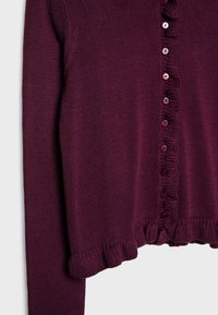 Cardigan tricoté violet prune avec manches longues, petits boutons ronds sur le devant et bords à volants à l'ourlet et sur la patte de boutonnage.