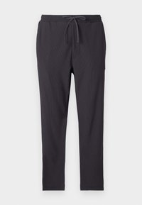 Mørk grå joggebukser med elastisk linning, snøring, sidelommer og ribbet tekstur gjennom hele buksen.