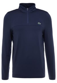 Marinblå långärmad tröja med halvdragkedja, med en ton-i-ton struktur och en liten grön broderad logotyp på bröstet.