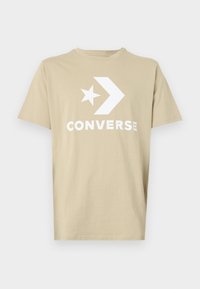 Khaki kokvilnas t-krekls ar lielu baltu "CONVERSE" logotipu un zvaigžņu grafiku. Klasisks apaļais kakls un īsās piedurknes.